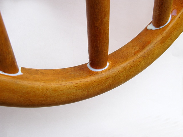 a close up of a wooden chair with snow on the top and bottom part of it