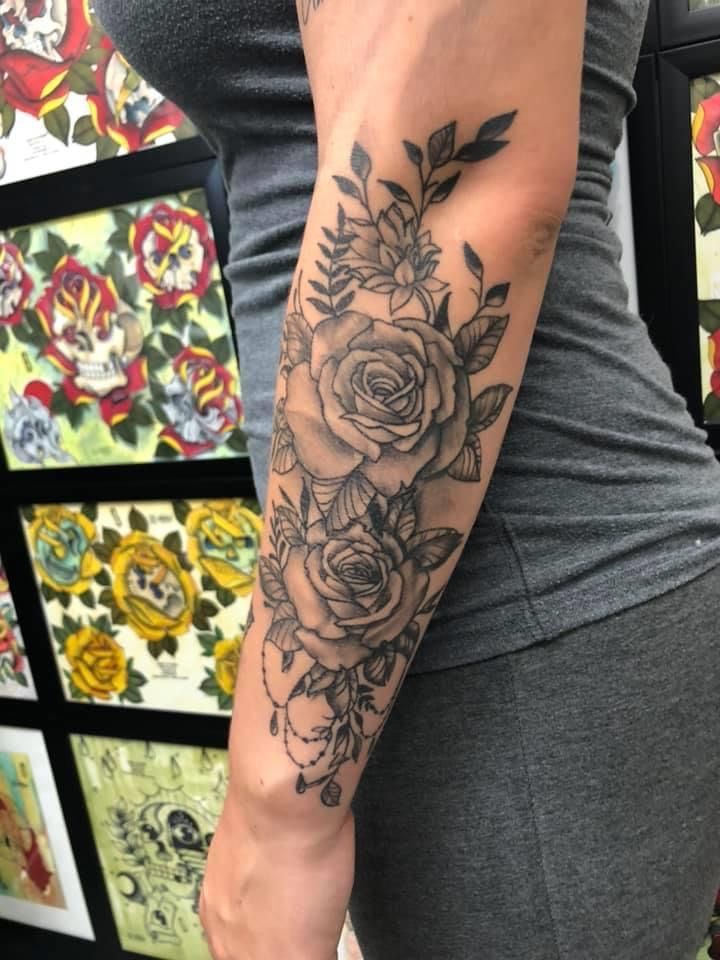 a woman's arm with flowers on it and tattoos on the side of her body