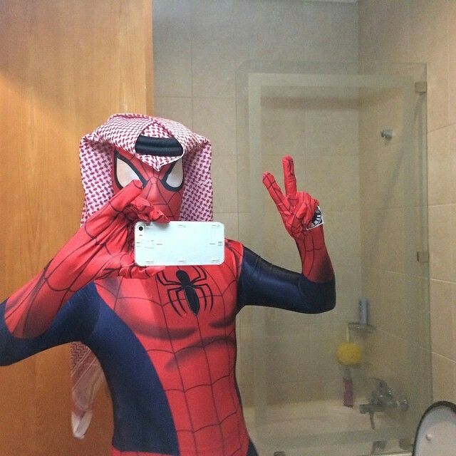 a man in a spiderman costume standing in front of a bathroom mirror with his hands up