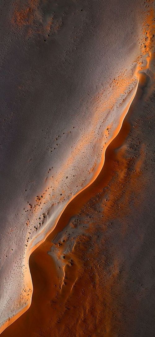 an aerial view of sand and water in the desert, with orange light coming from above