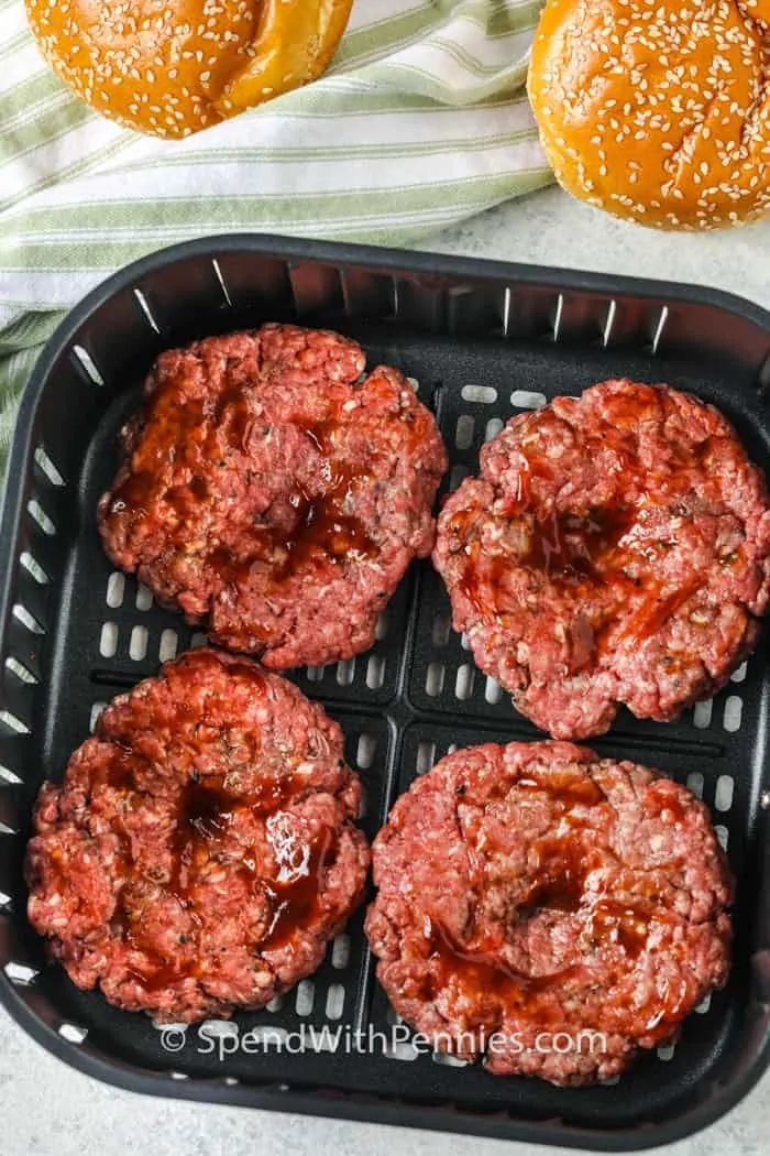 hamburger patties with ketchup in a bun on a grill pan next to pretzels