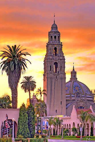 a large building with a clock tower next to palm trees and other buildings in the background