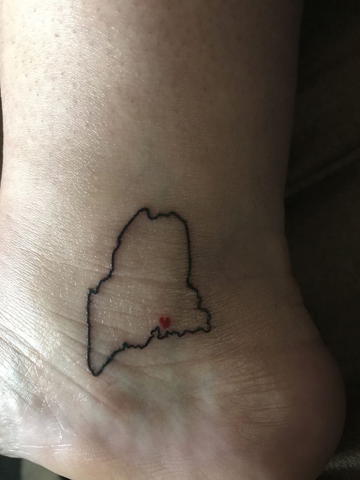 a small tattoo on the ankle of a woman's foot with a red heart