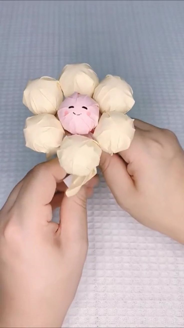 a person holding a small stuffed animal in the palm of their hand on top of a bed