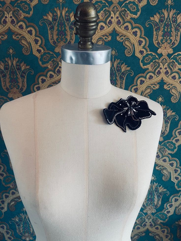 a white mannequin with a black flower on it