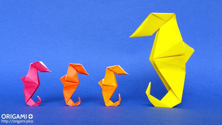 three origami seahorses standing next to each other on a blue background