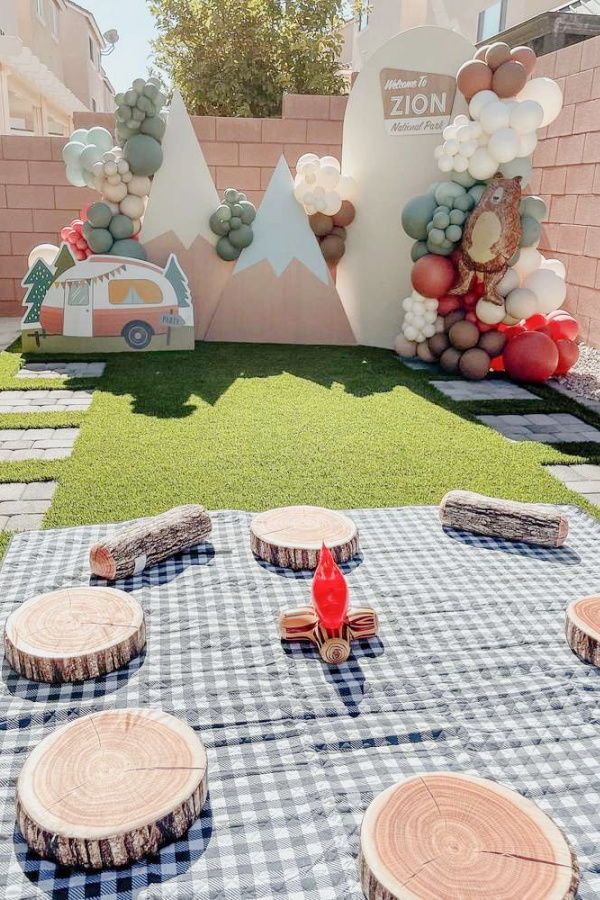 an outdoor picnic area with wood slices and balloons