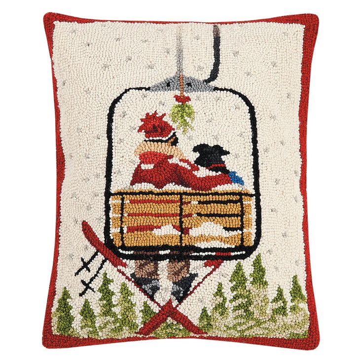 an embroidered pillow with a skier on the ski lift and pine trees in the background