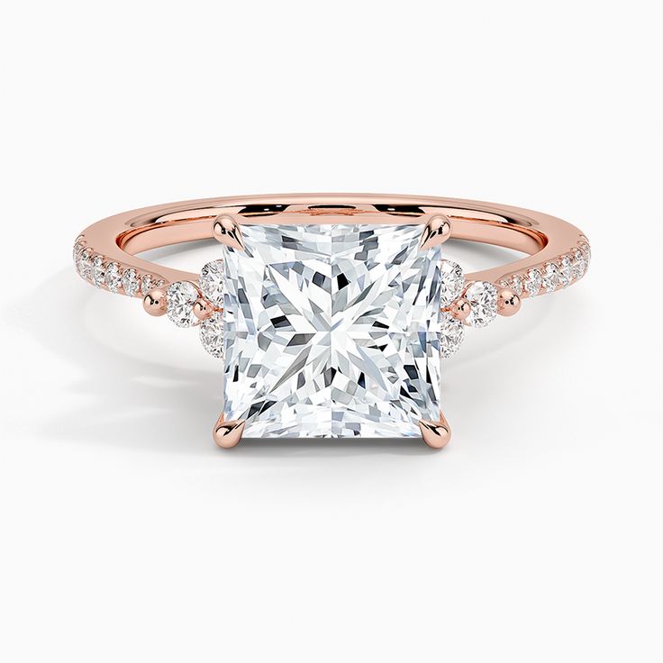 a princess cut diamond ring with pave diamonds on the band and shoulders, set in 18k rose gold