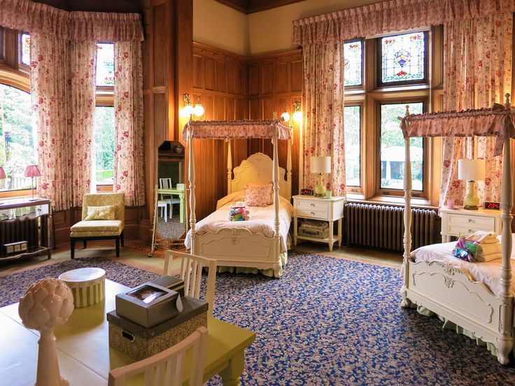 a bedroom with two beds, chairs and windows in the wall to the ceiling are decorated with floral curtains