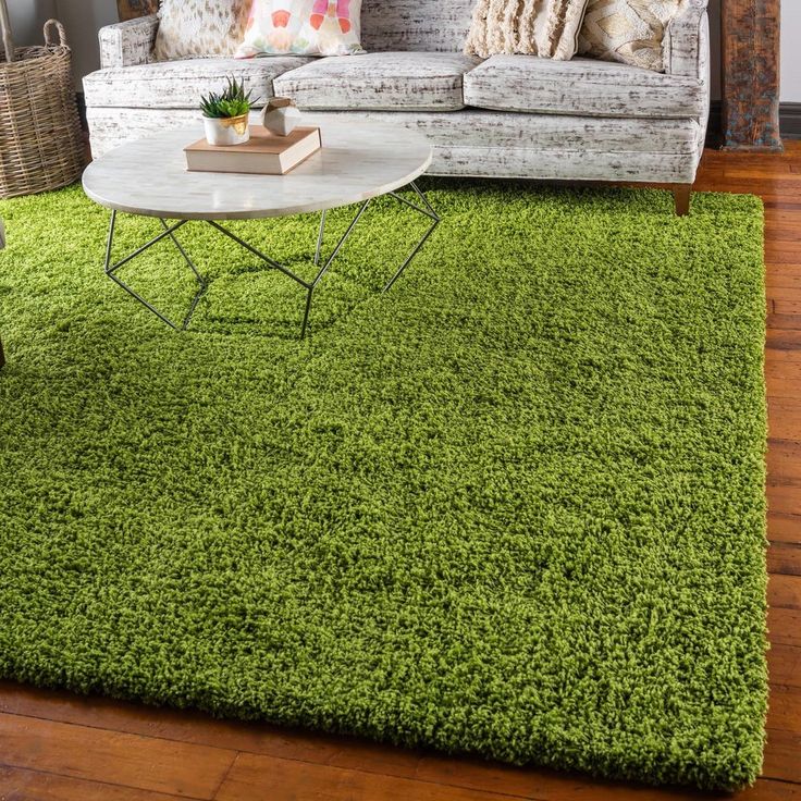 a living room with green rugs on the floor and a white couch in front of it