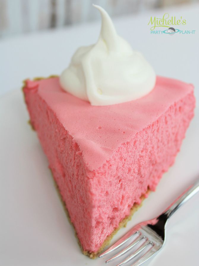 a piece of pink cheesecake with whipped cream on top and a fork next to it