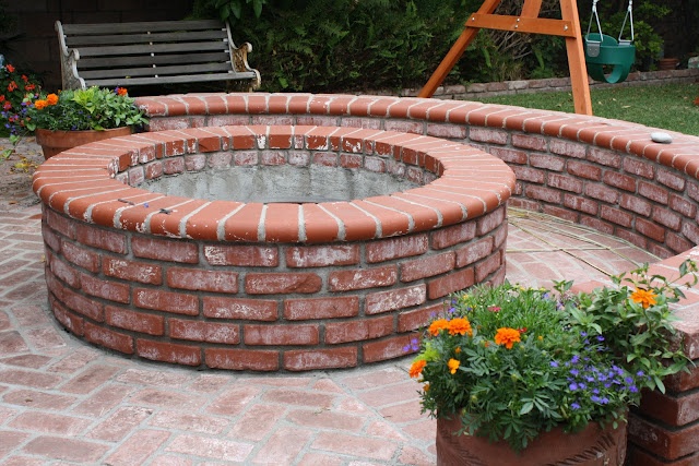 a brick fire pit surrounded by potted plants