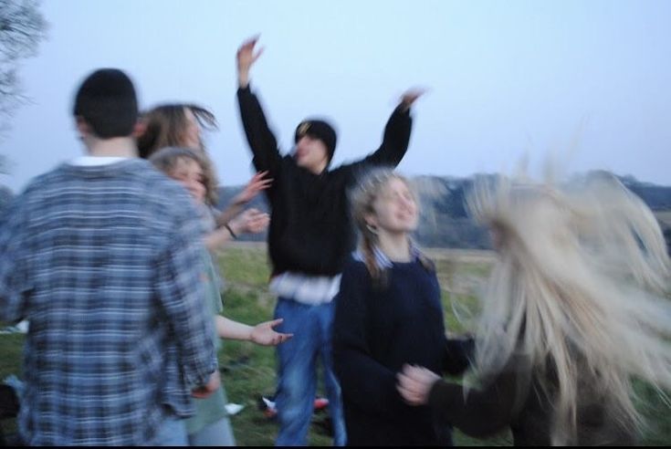 a group of people standing in a field with their arms up and one person holding his hands out