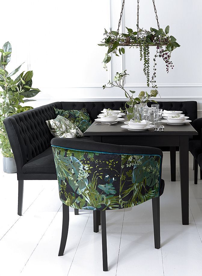 a dining room table with black chairs and green plants