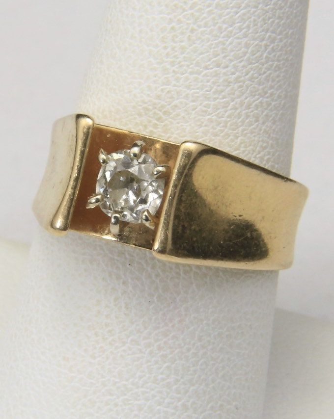 a gold ring with a white diamond on the top and bottom, sitting on a napkin