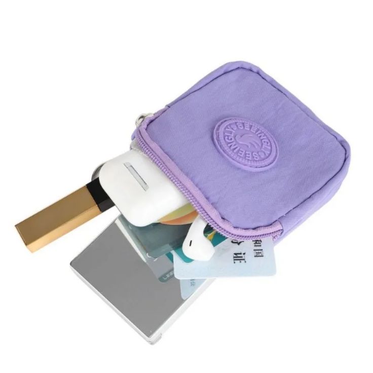 a purple bag with various items inside it on top of a white surface and in the background is a laptop