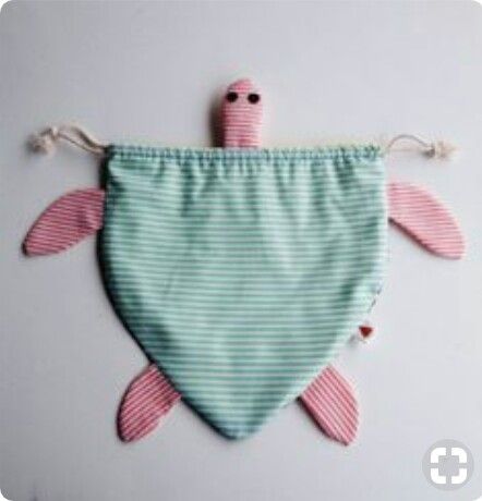 a green and white striped bib with a pink turtle on the front, hanging from it's side