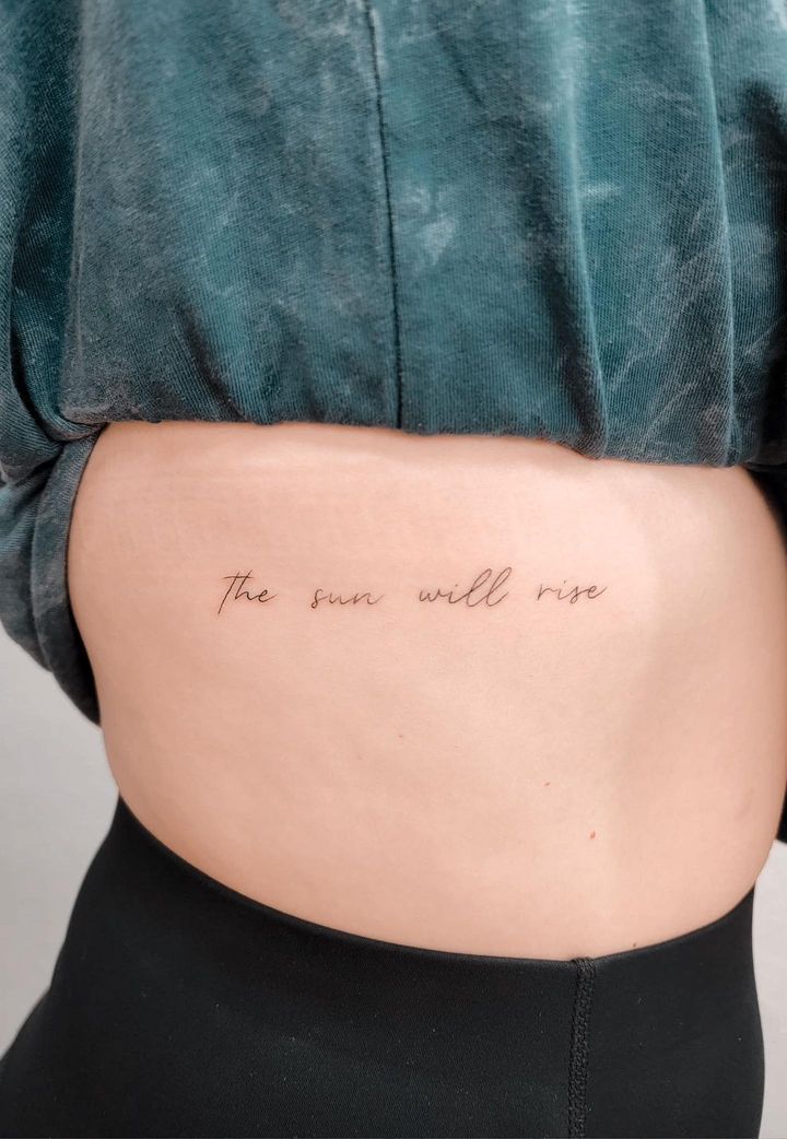 the back of a woman's stomach with an inscription on it that reads, the sun will rise