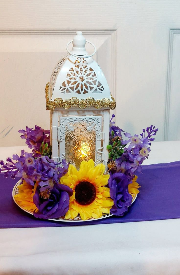 a white lantern with purple and yellow flowers on a plate