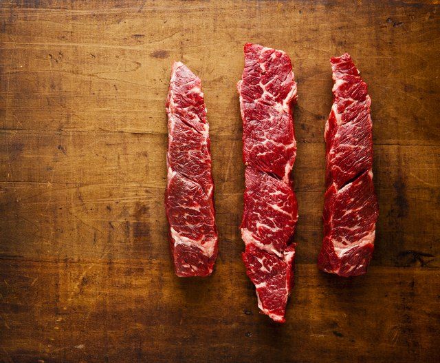 three pieces of raw meat sitting on top of a cutting board next to each other