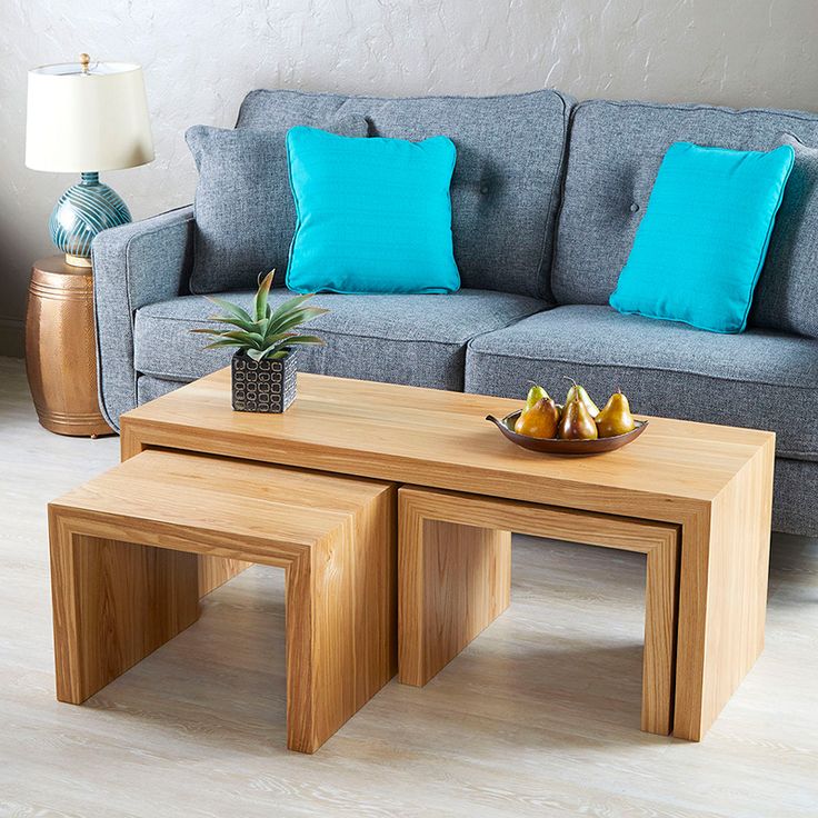 two wooden tables sitting on top of a hard wood floor next to a gray couch