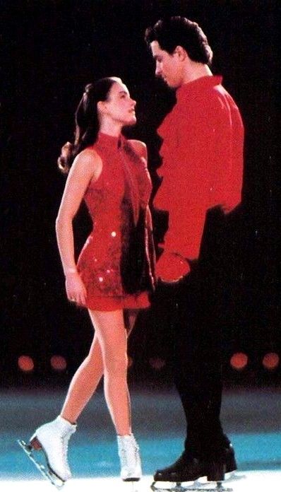 a man and woman standing next to each other in front of a stage with lights