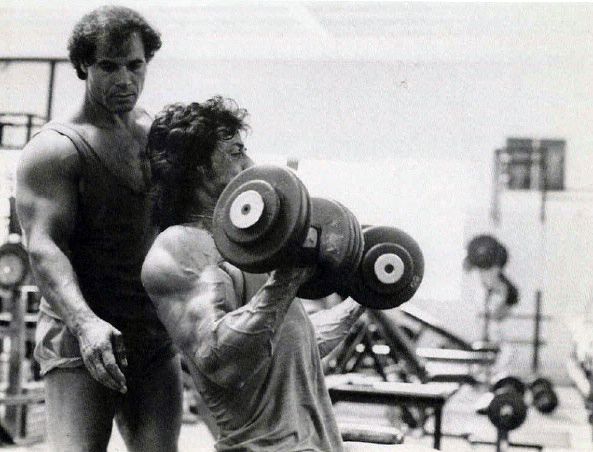 a man lifting a barbell in front of another man