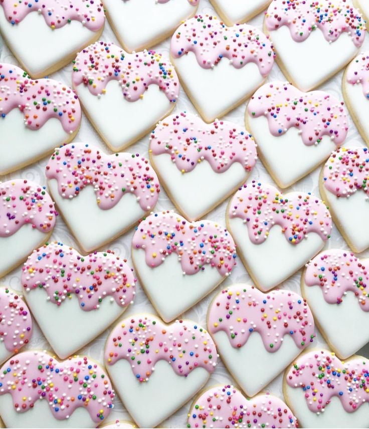 decorated cookies arranged in the shape of hearts and unicorns with sprinkles