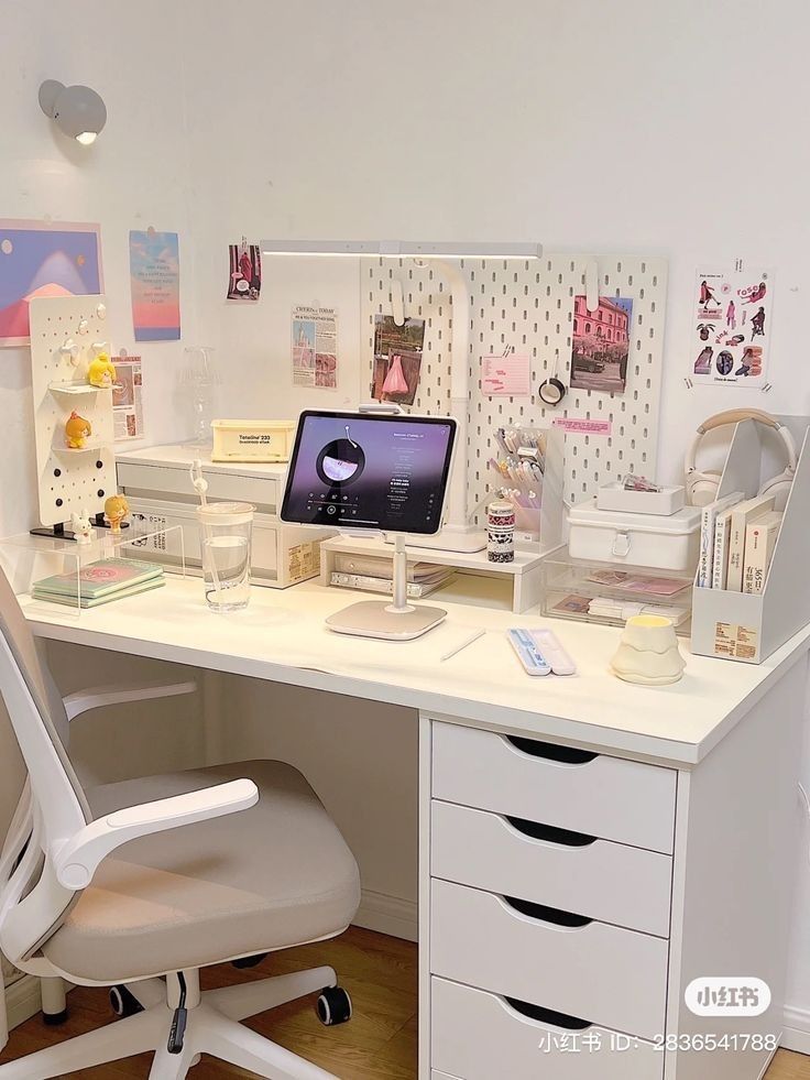 a white desk with a laptop computer on top of it next to a chair and other office supplies