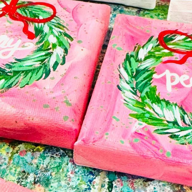 two pink painted boxes with holly wreaths on them and the words pom written in white