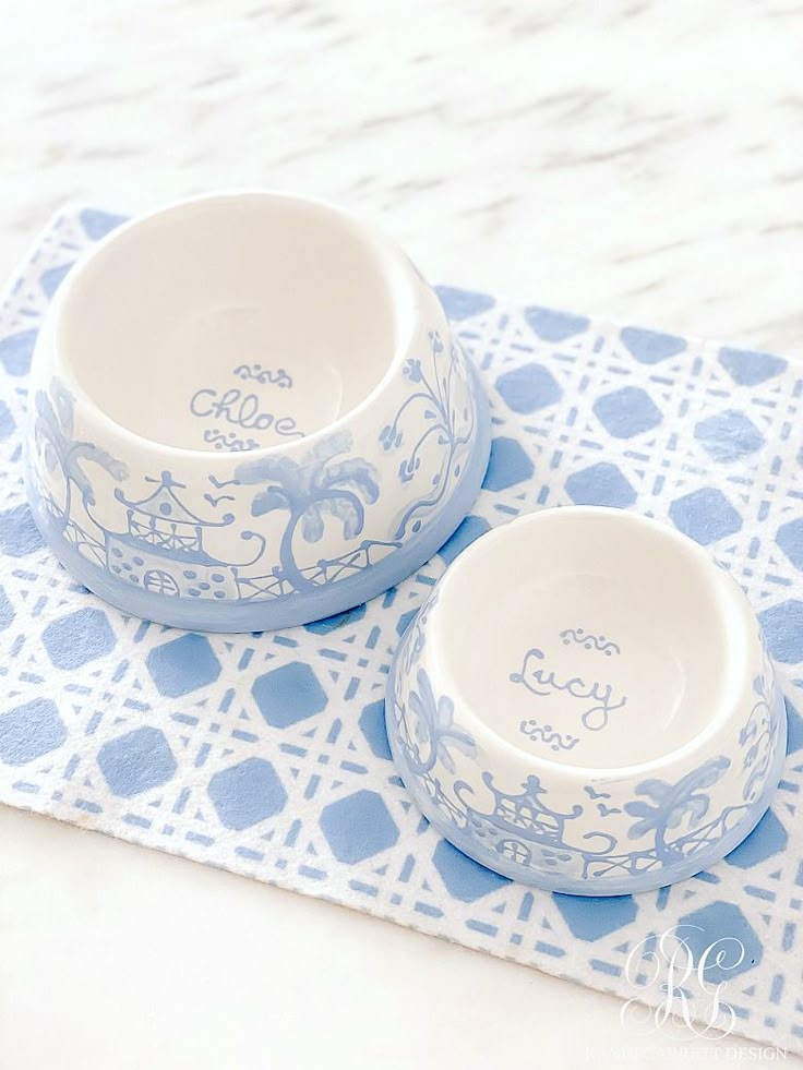 two blue and white bowls sitting on top of a place mat with the words hello kitty written on them