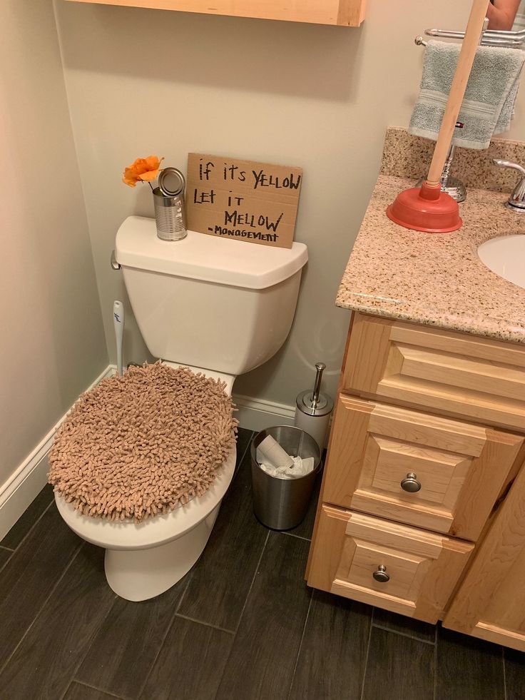 a bathroom with a toilet, sink and wooden cabinet in it's center area