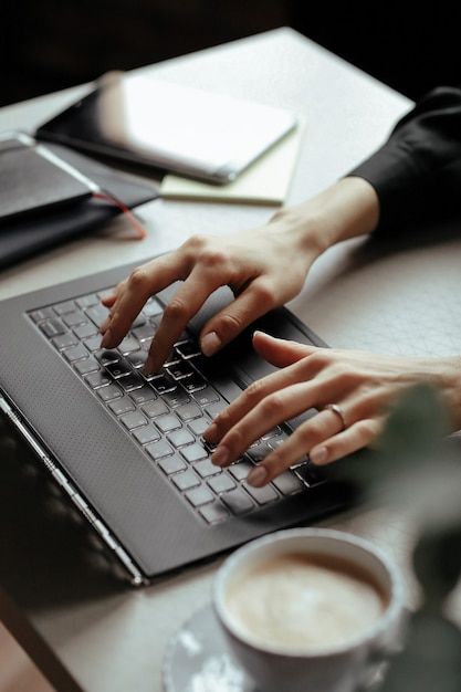 a person using a laptop computer on a table with a cup of coffee in front of them