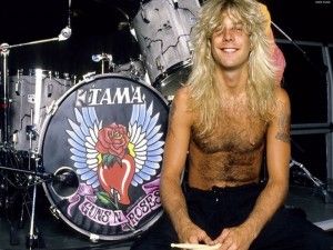 a shirtless man sitting in front of a drum set