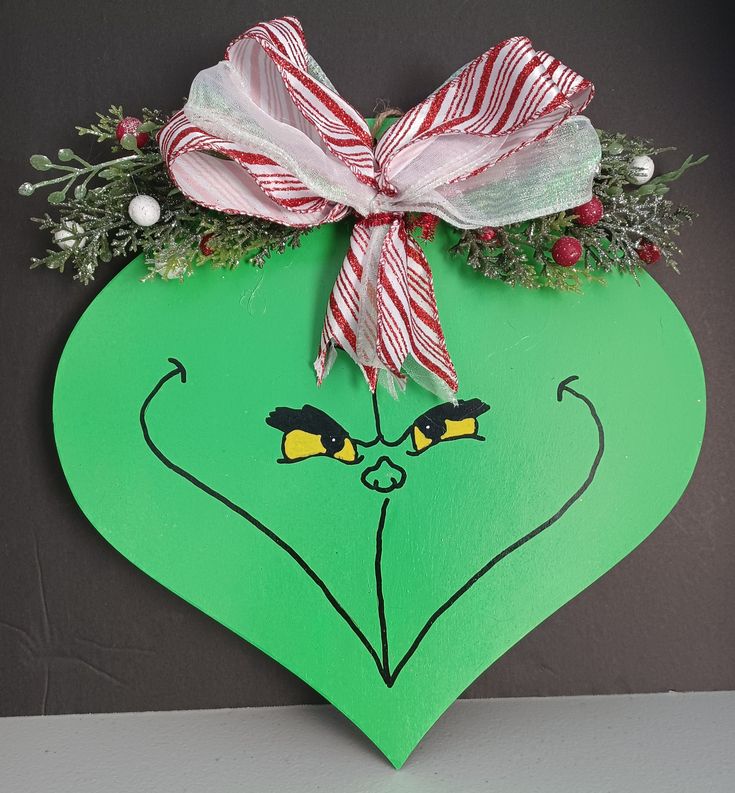 a green heart with a red and white bow hanging from it's side on a wall