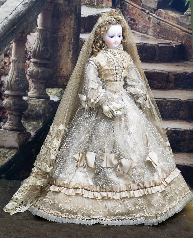 a doll dressed in an old fashion wedding gown and veil is sitting on some steps