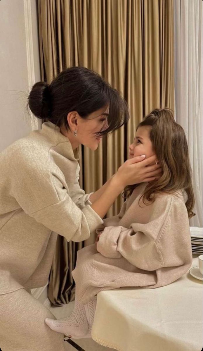 a woman sitting in front of a mirror brushing her teeth with another woman standing next to her