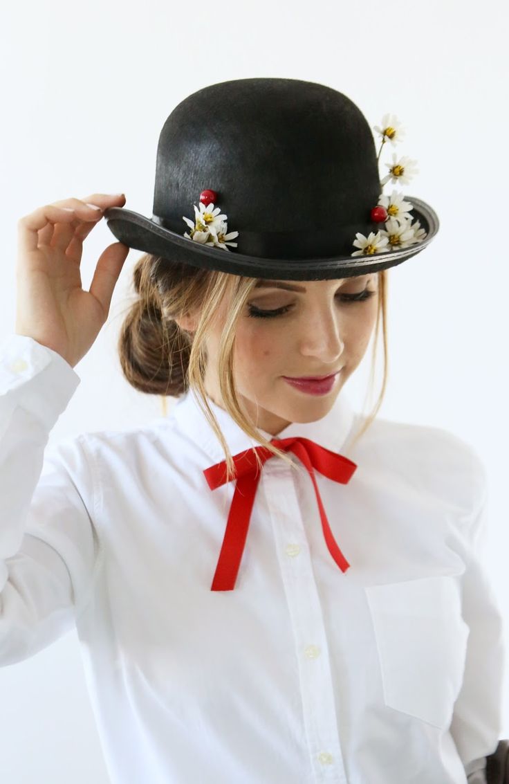 a woman wearing a white shirt and black hat with flowers on the top of it