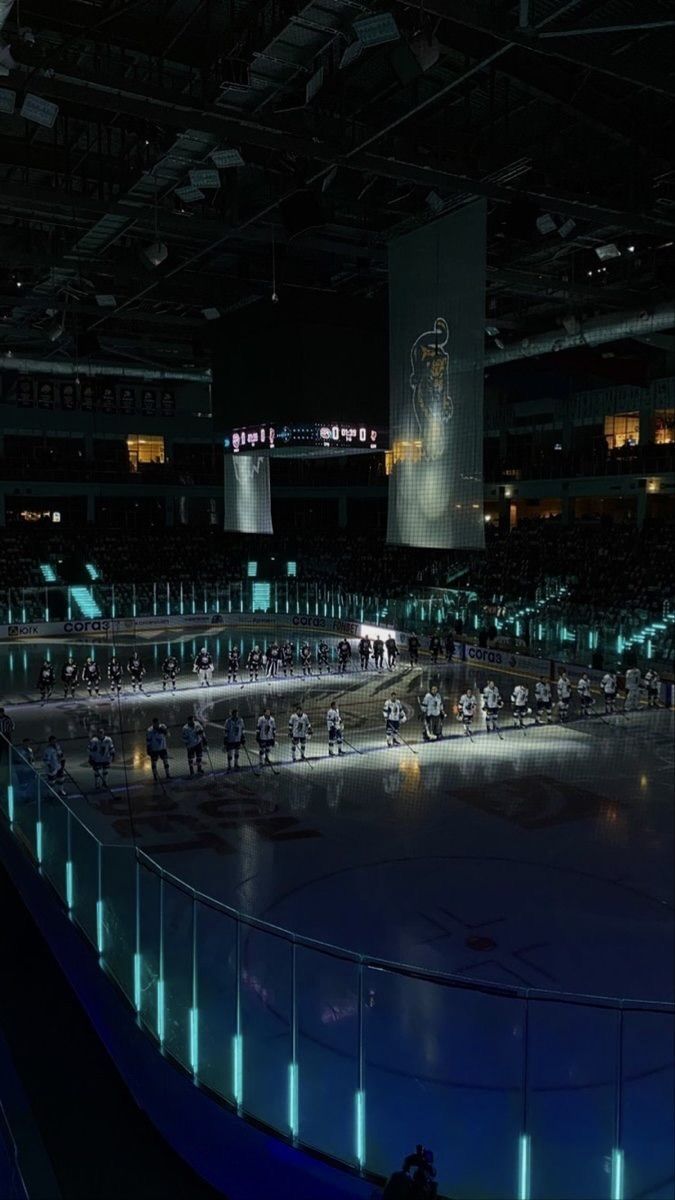 the ice rink is lit up at night for an ice hockey game in which players are playing