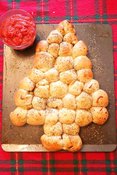 a christmas tree made out of bread on top of a cutting board next to a bowl of ketchup