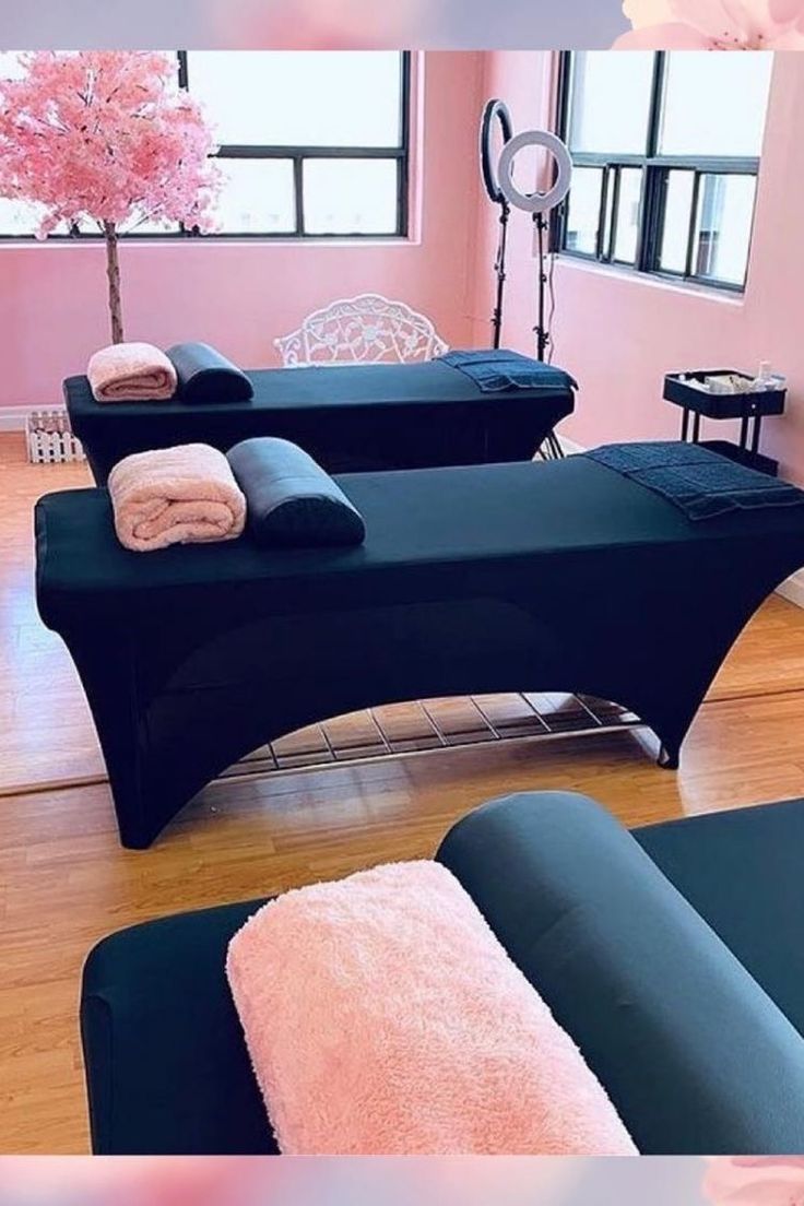 two black couches with pink towels on them in a room that has wooden floors