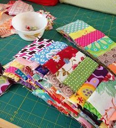 a cutting board topped with lots of different colored pieces of fabric next to a bowl