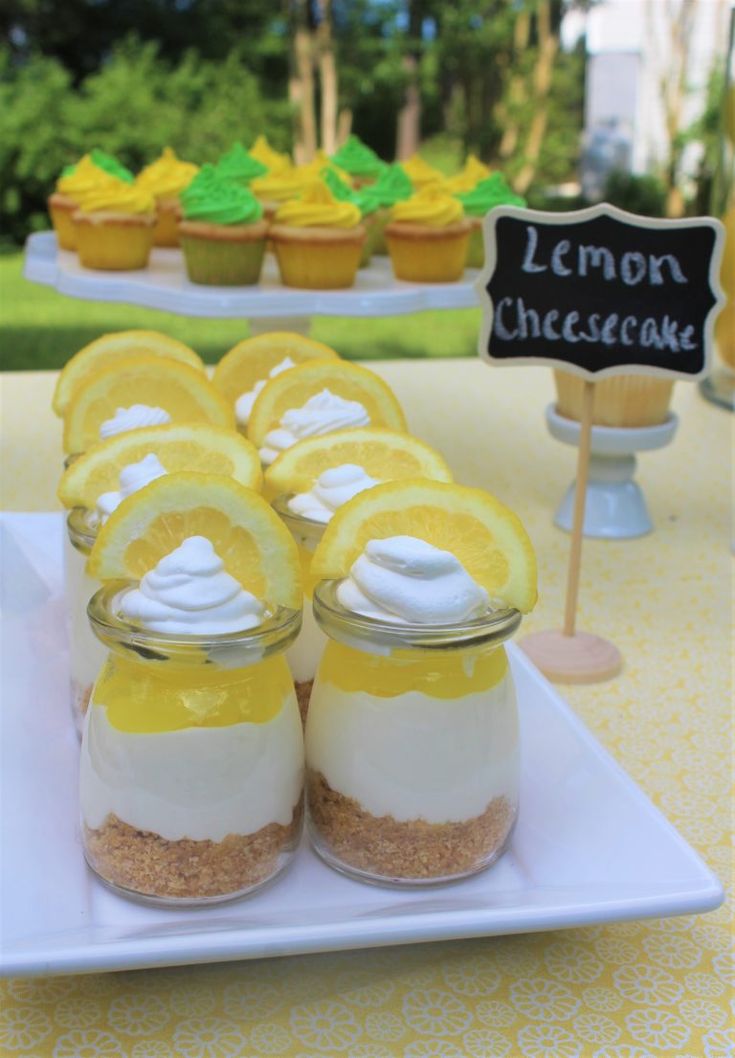 lemon cheesecakes in jars on a table with cupcakes and other dessert items