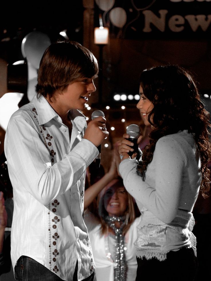 a man and woman singing into microphones in front of an audience at a new year's eve party