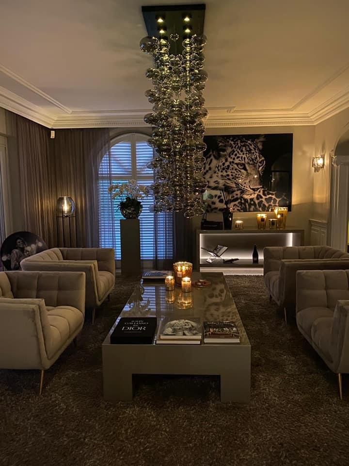 a living room filled with furniture and a tall chandelier hanging from the ceiling