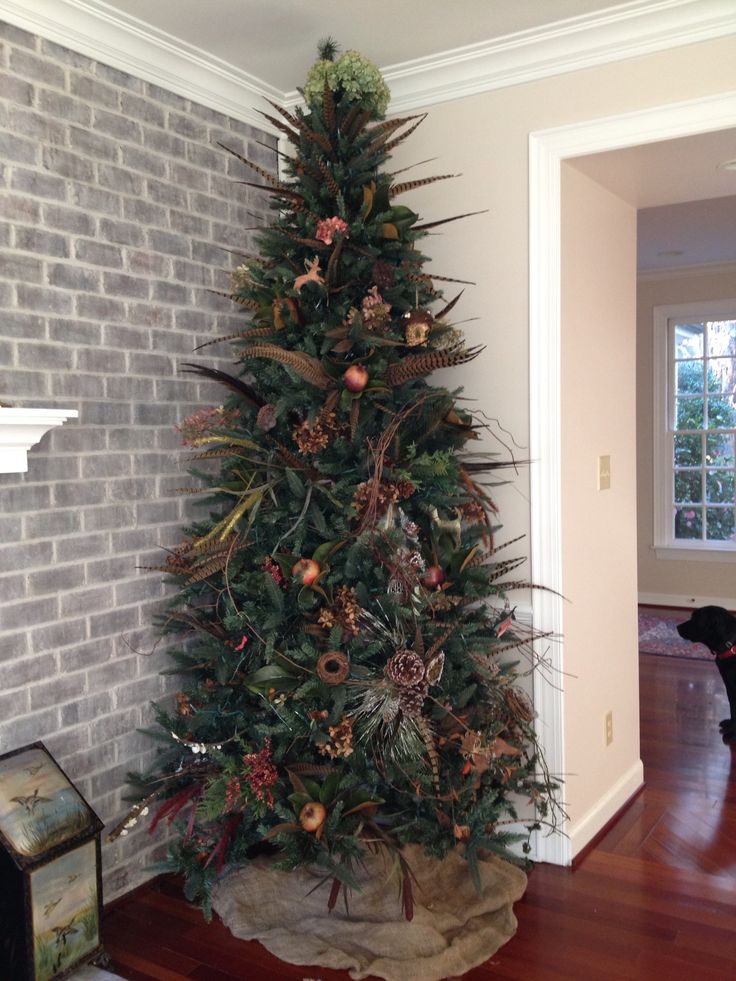 a decorated christmas tree in the corner of a room with a brick wall and wood floors