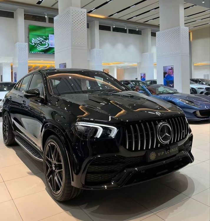 a black mercedes suv is on display in a showroom with other cars behind it