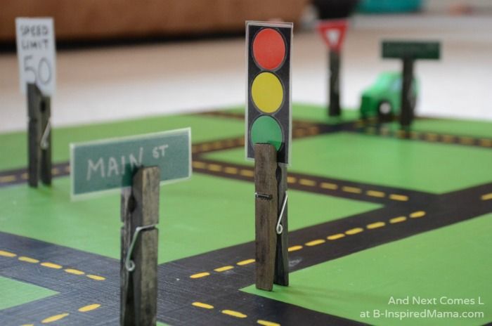 a traffic light sitting on top of a green floor next to a street sign and road signs