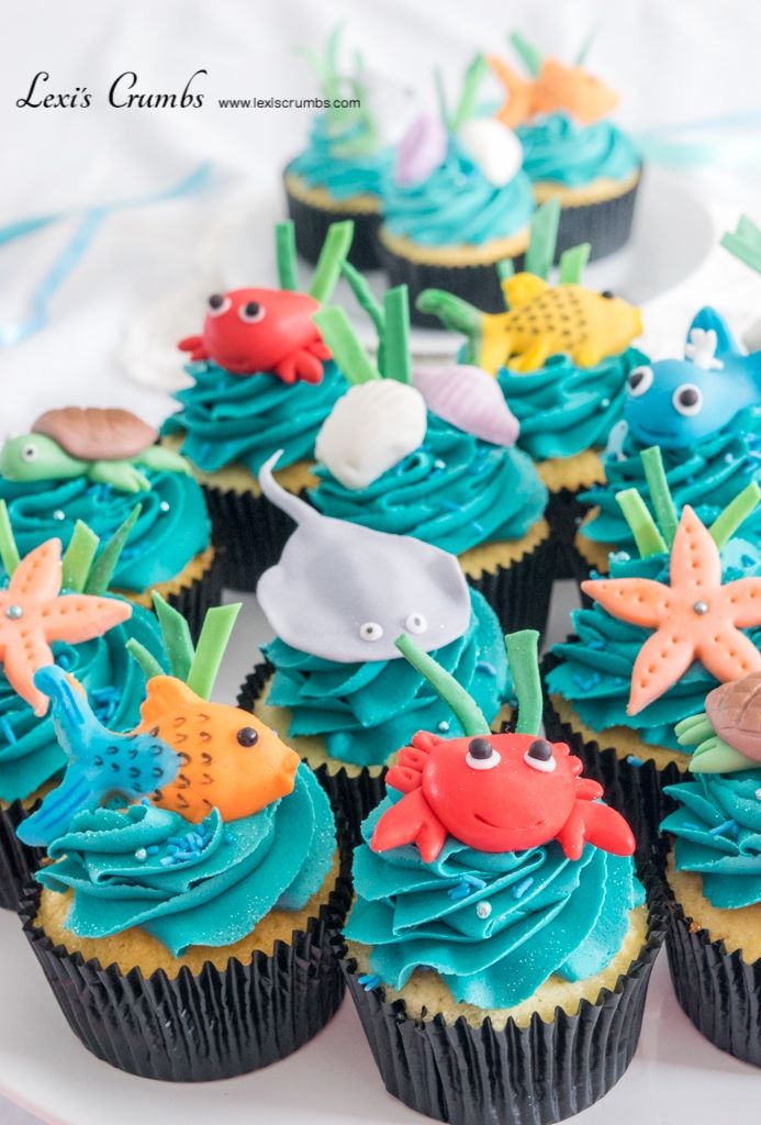 cupcakes with blue frosting and sea creatures on them sitting on a plate